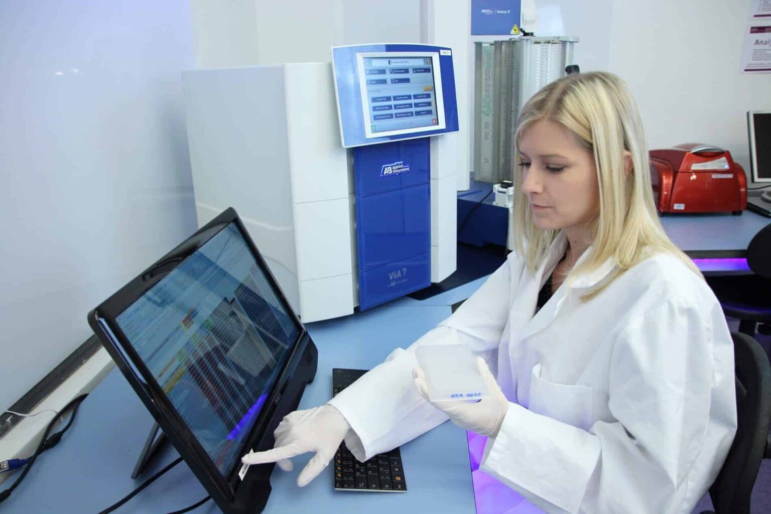 a woman in a lab coat and gloves using a computer