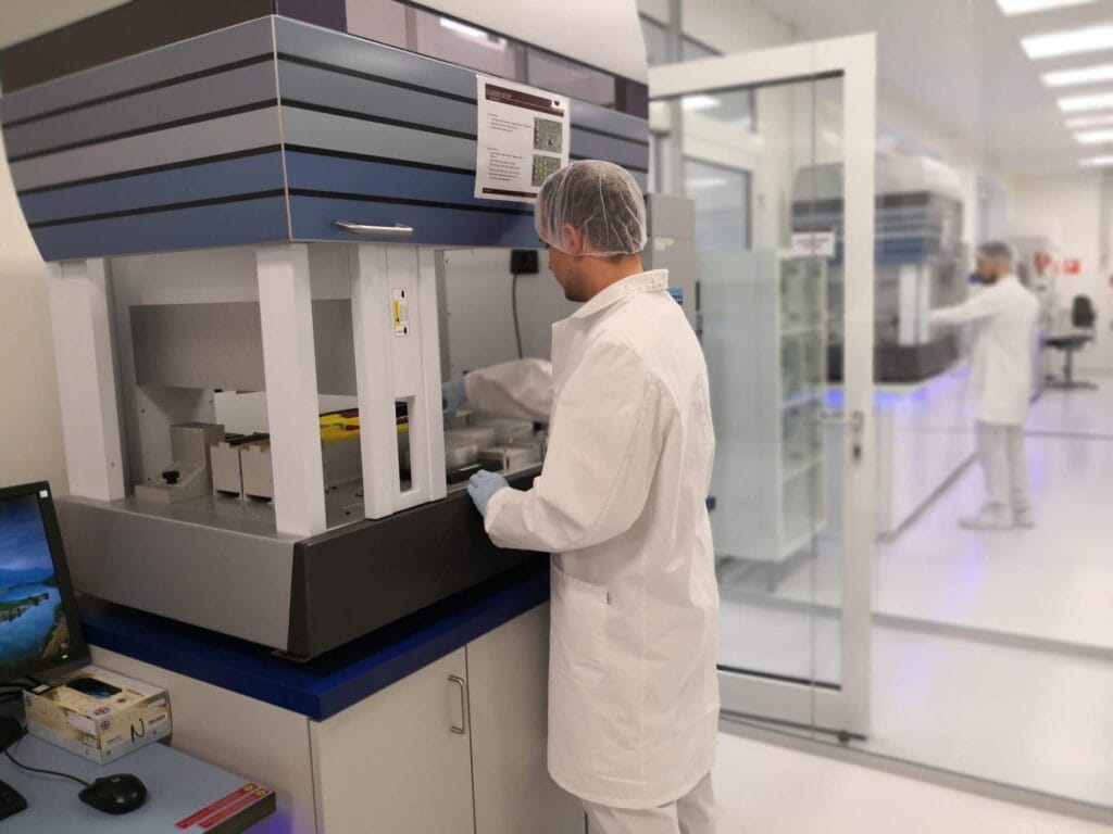 a man in a white coat and plastic gloves working in a laboratory