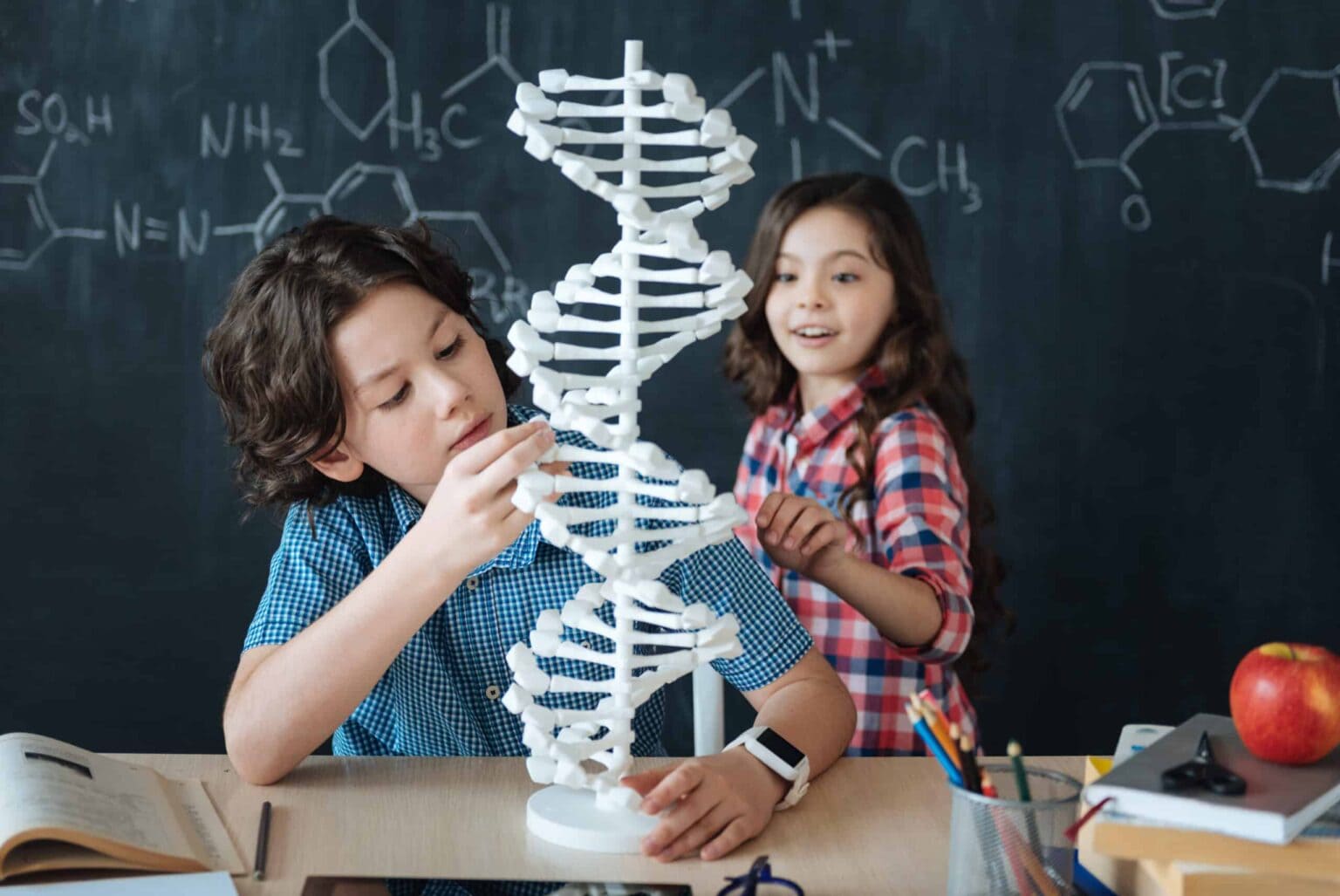 a boy and girl looking at a model of dna